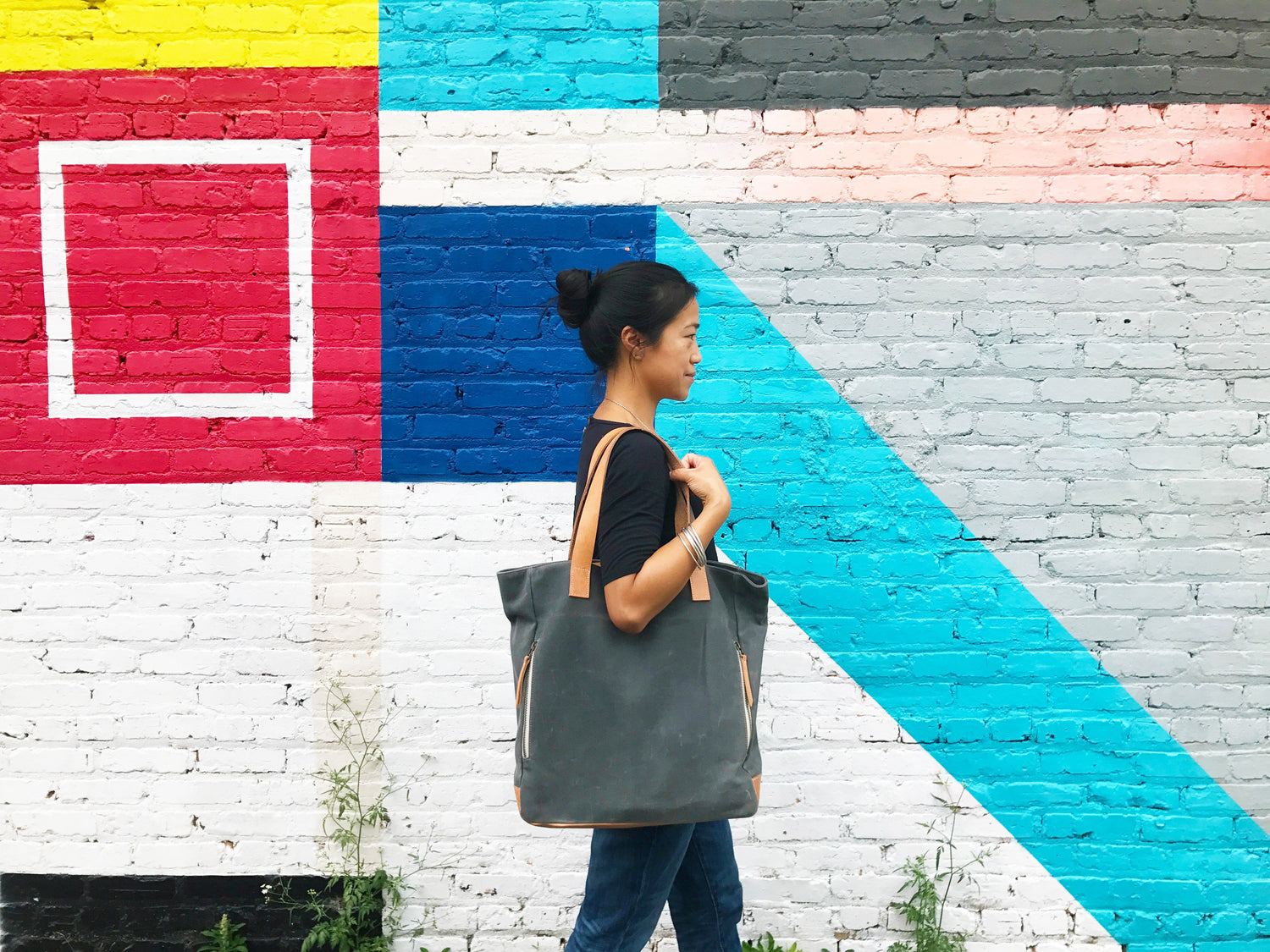 Morning Person, charcoal bag, against an Atlanta mural. 